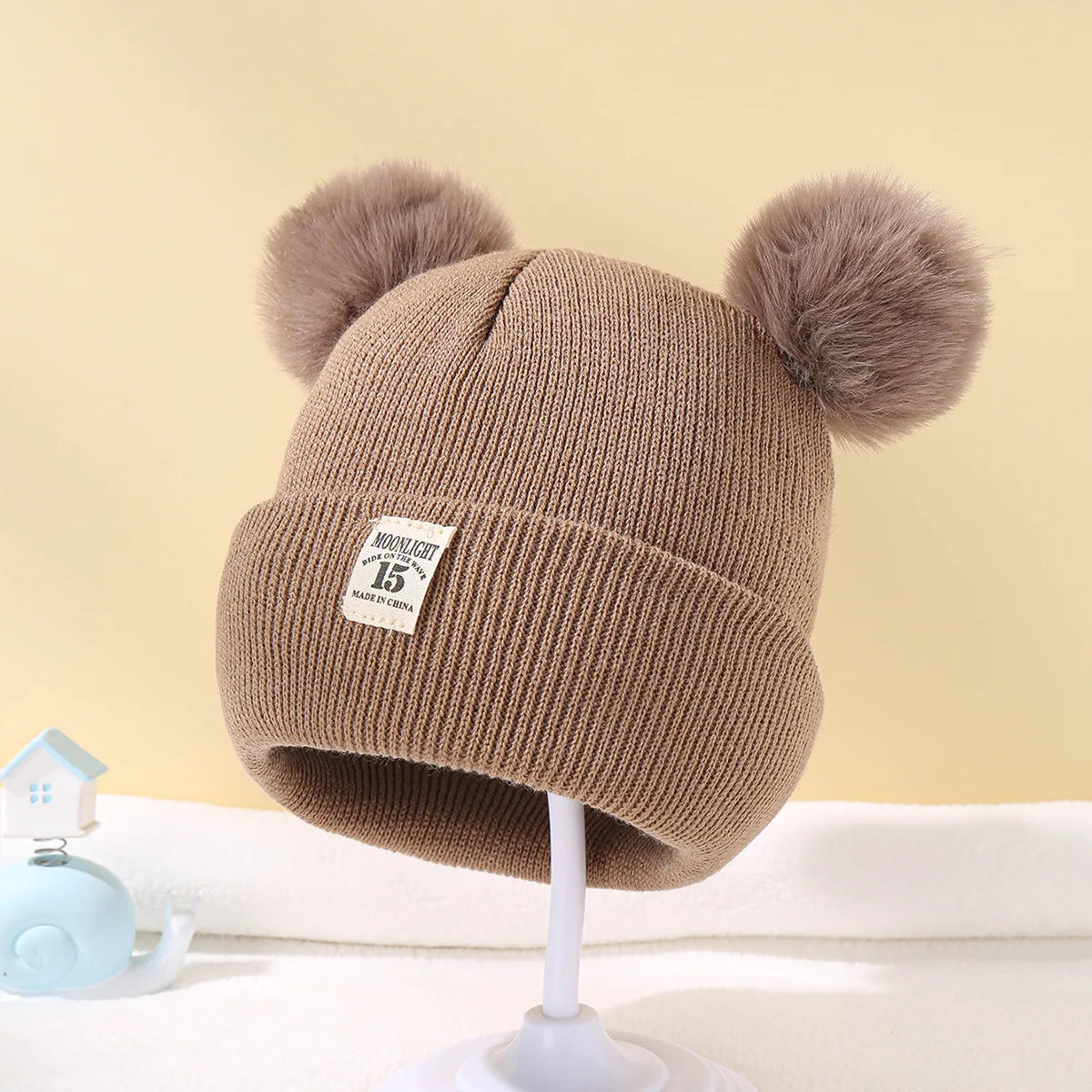BORA kids pom pom hat in brown with fluffy pom poms for stylish winter warmth.